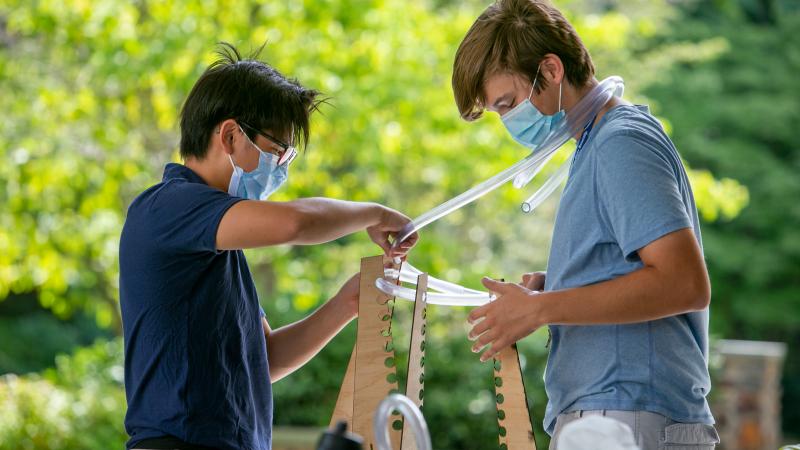 two boys working outside with tubes